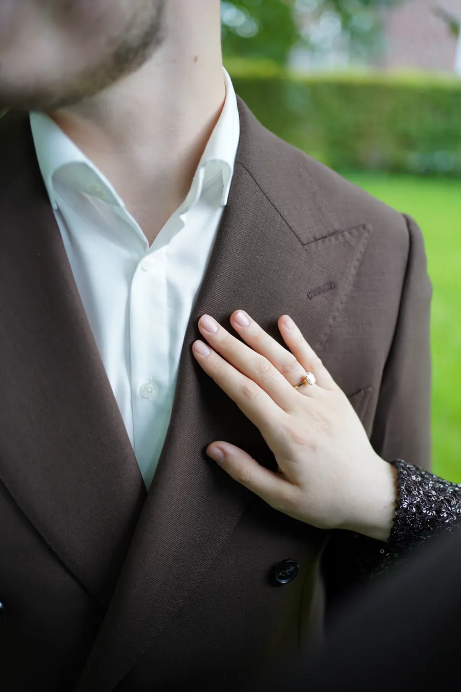 Detail: ihre Hand mit Ring auf seinem Sakko