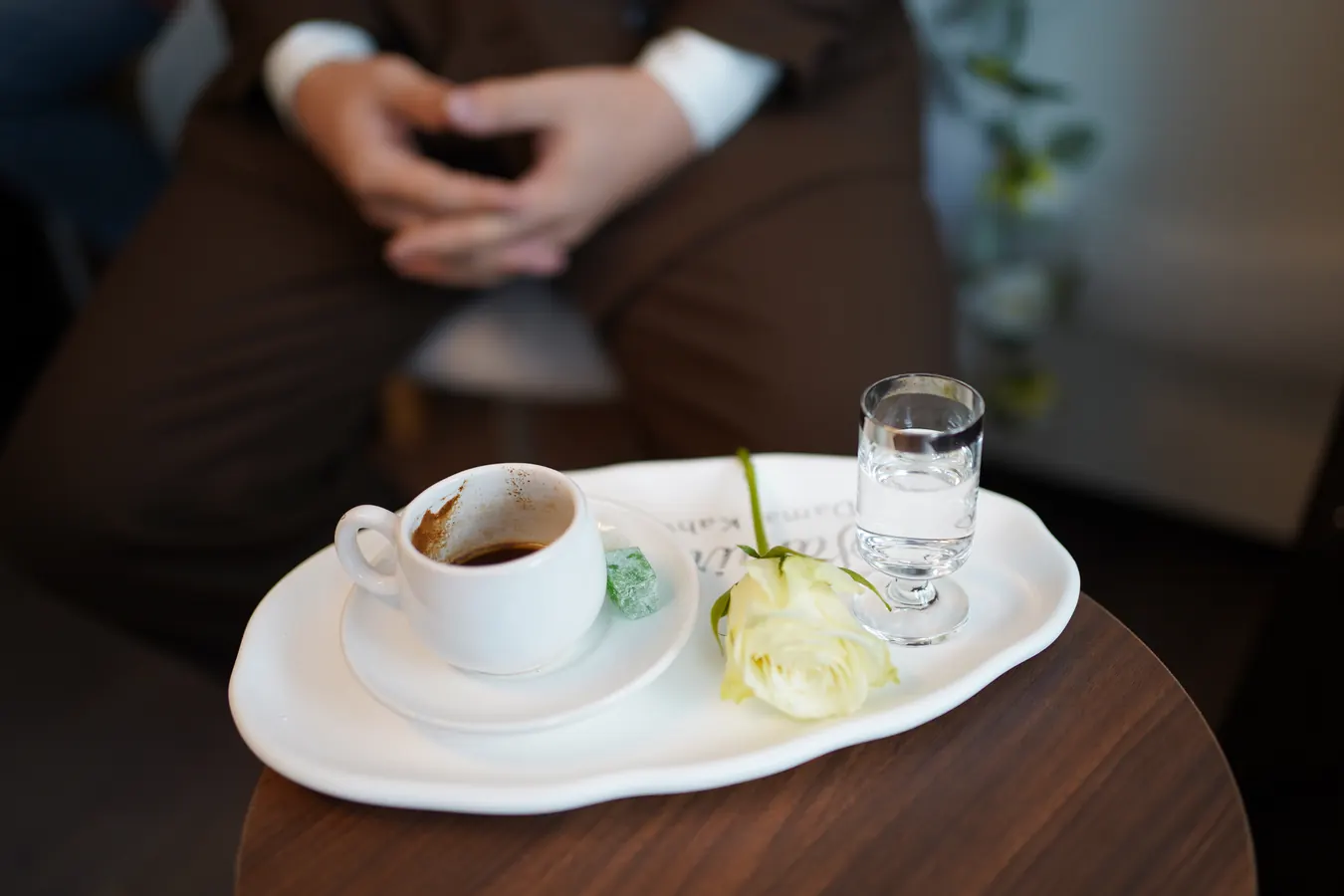 Detail: Kaffeetasse, Wasserglas und weiße Rose auf einem Tablett