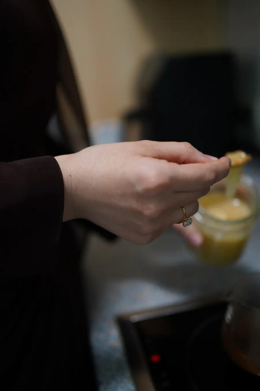 Detail: Hand mit Löffel über einem Glas