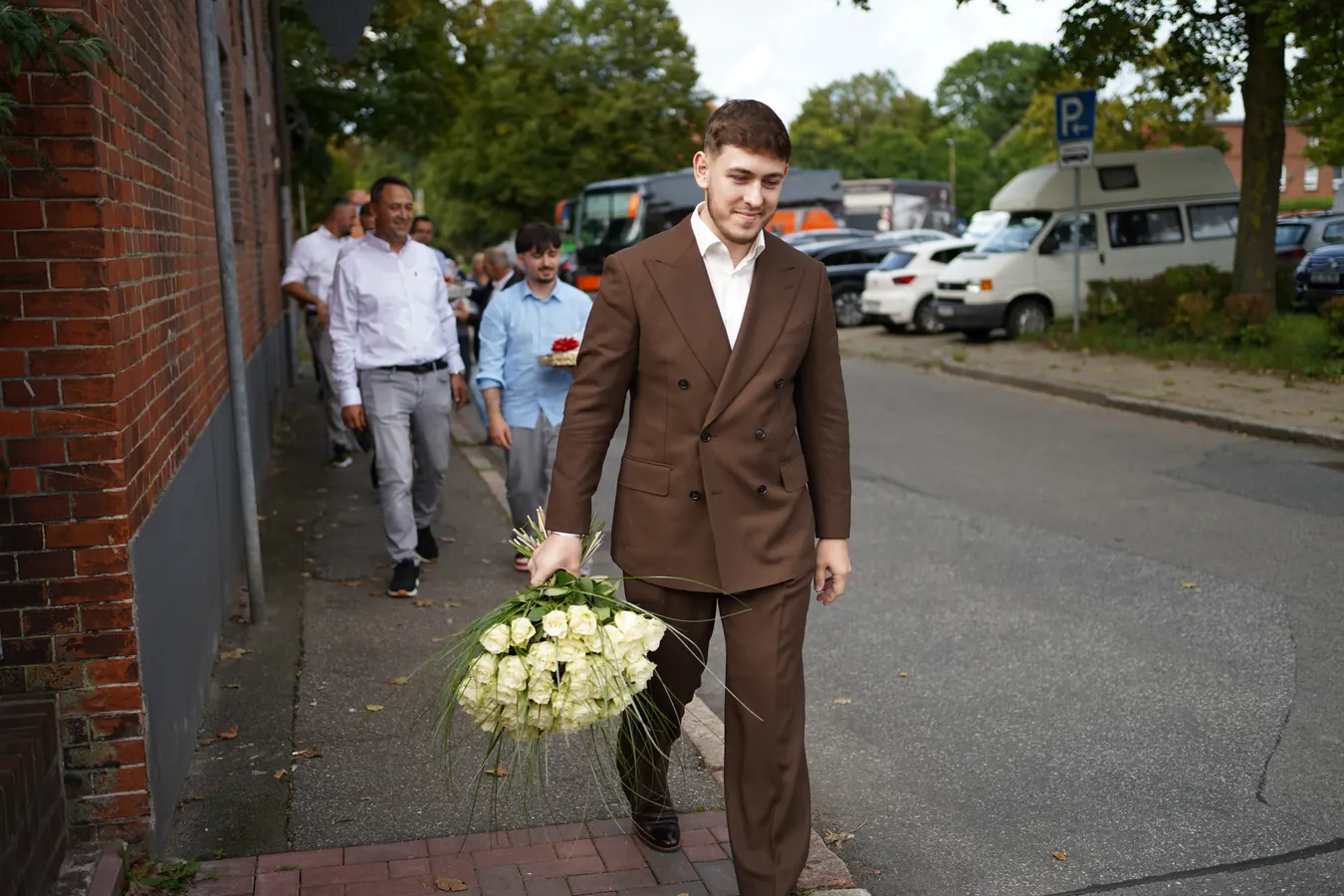 Der Bräutigam kommt mit einem Strauß weißer Rosen